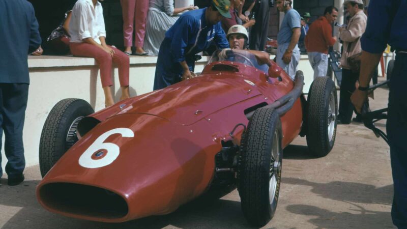 Maserati drivers Harry Schell (in car), Juan-Manuel Fangio (blue) and Jean Behra (red sweater) in the pits before the 1957 French Grand Prix in Rouen. Photo: Grand Prix Photo