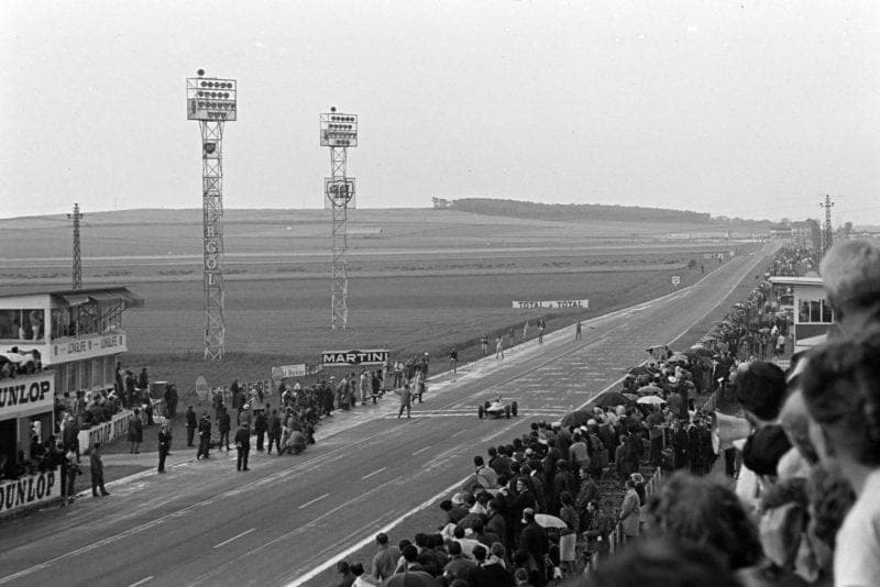 Jim Clark, Lotus 25 Climax, crosses the finish line and takes the chequered flag.