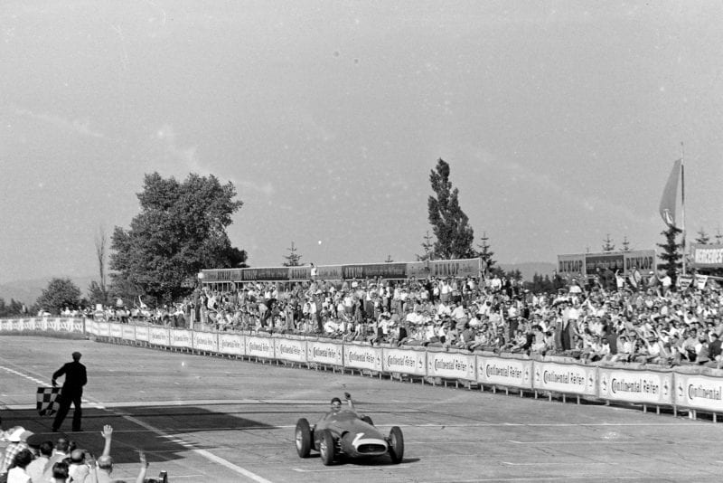 Juan Manuel Fangio crosses the finishing line and passes the chequered flag in his Maserati 250F