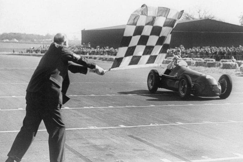 Giuseppe Farina takes the chequered flag to win the 1950 British Grand Prix at Silverstone