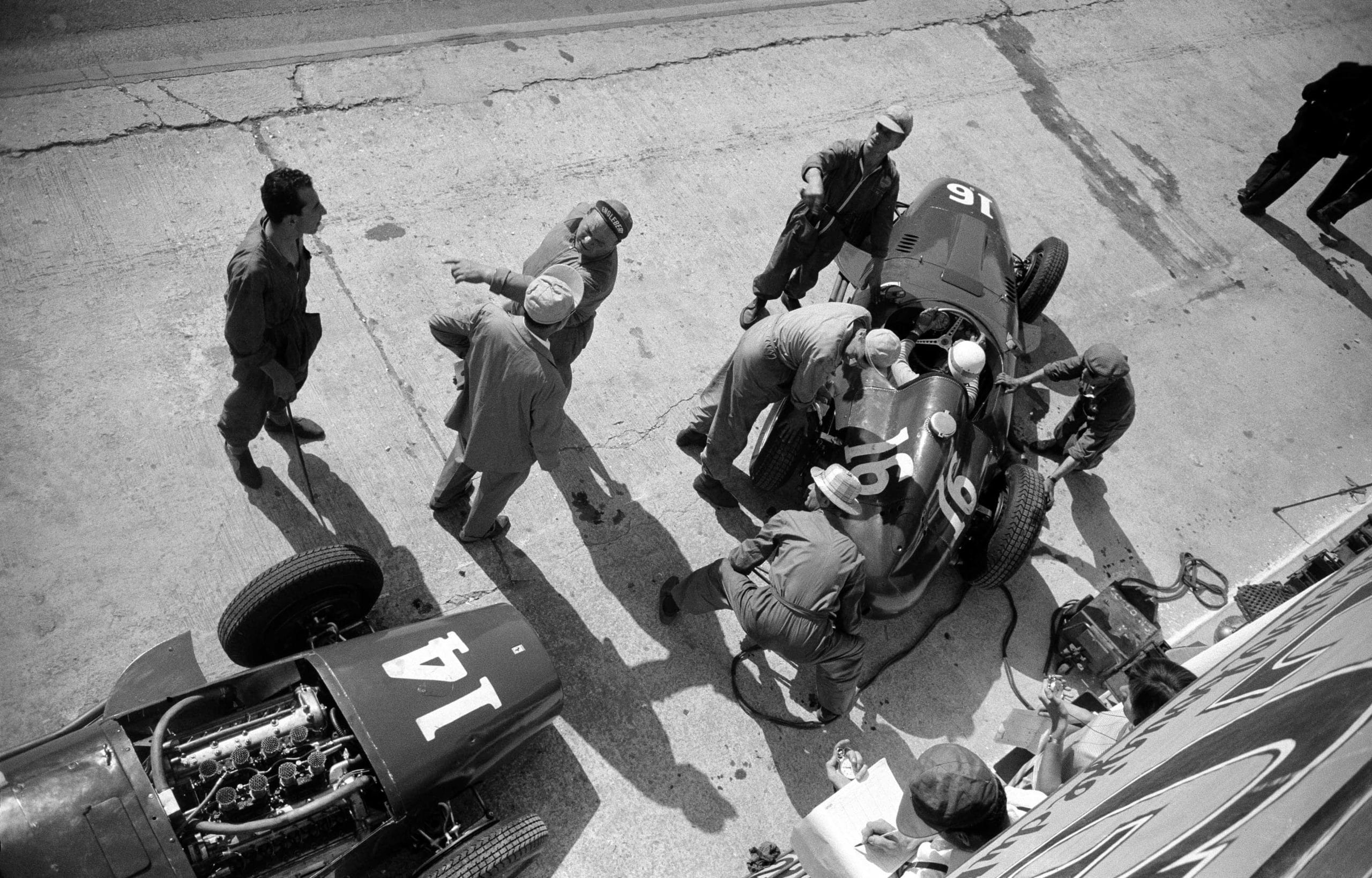 The French Grand Prix; Rouen-les Essarts, July 7, 1957. Here is another wonderful photograph from the 1957 French Grand Prix taken during practice at the Ferrari pits. N. 16 is the car of Maurice Trintignant which is being just fired up and n. 14 is the car for Mike Hawthorn. Meanwhile, mechanic Luigi Parenti directs the orchestra at center stage! (Photo by Klemantaski Collection/Getty Images)