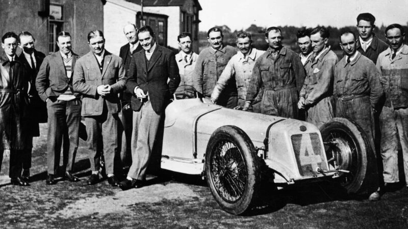 Robert Benoist with a cigarette, leaning against a Delage 15-S8, 1927. A group of mechanics stand to the right of the car. The racing drivers Albert Divo and Edmond Bourlier stand to the left of Benoist; Divo immediately to the left of him, and Bourlier to the left of Divo. In 1927 Benoist won the French, Spanish, European and British Grand Prix in a Delage 15-S8. (Photo by National Motor Museum/Heritage Images/Getty Images)