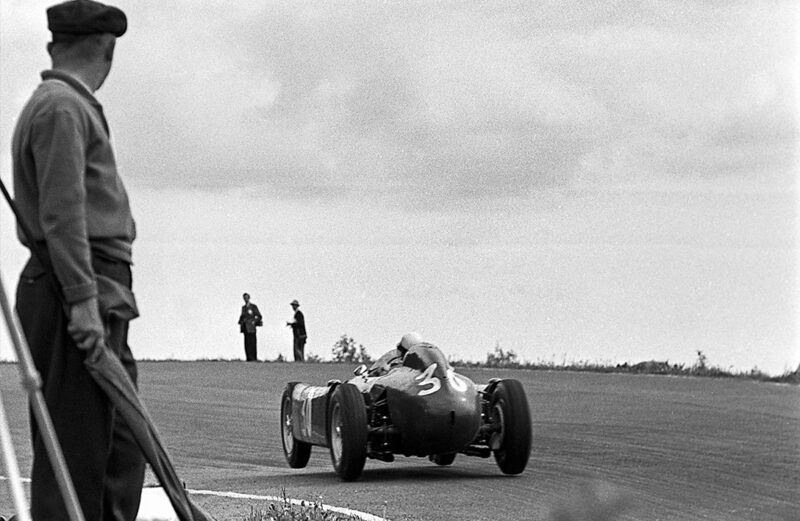 Ferrari of Eugenio Castellotti lifts a wheel over a bump in the 1955 Belgian Grand Prix