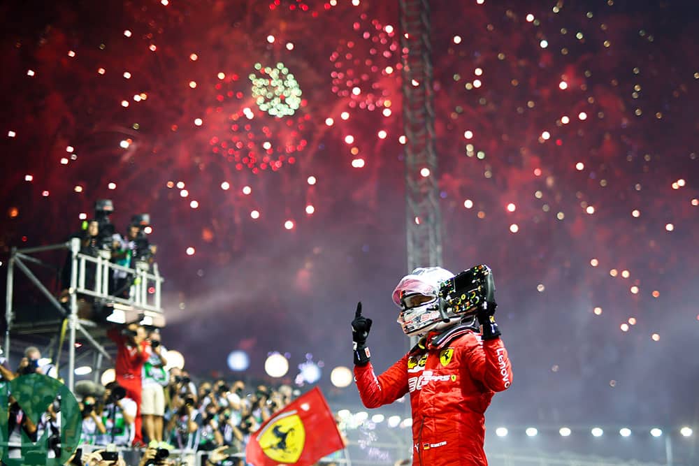 Sebastian Vettel holds his steering wheel in the air beneath fireworks after winning the 2019 Singapore Grand Prix