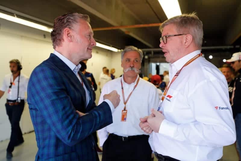 Sean Bratches speaks with Ross Brawn and Chase Carey in an F1 pit