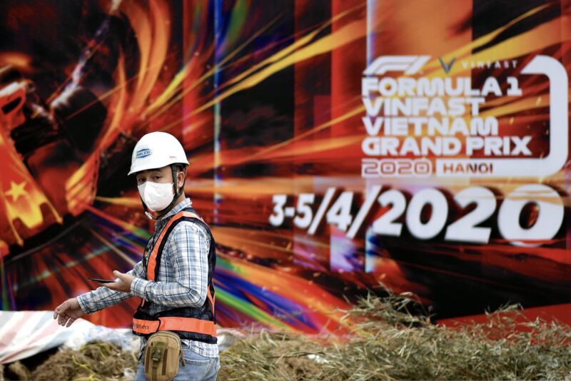 Worker with face mask in front of F1 Vietnamese Grand Prix poster