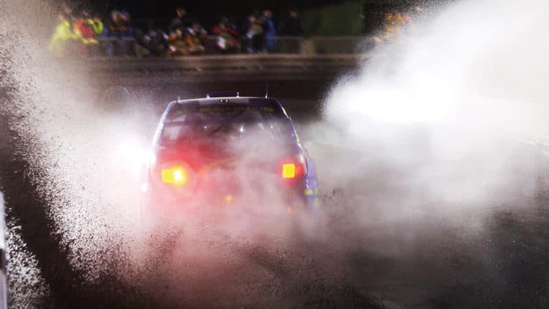 Subaru Impreza of Richard Burns sprays water and mud during a night stage