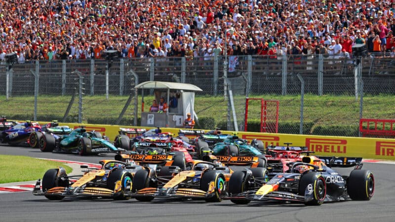 Oscar Piastri, Lando Norris (both McLaren-Mercedes) and Max Verstappen (Red Bull-Honda) side by side in the first corner after the start of the 2024 Hungarian Grand Prix