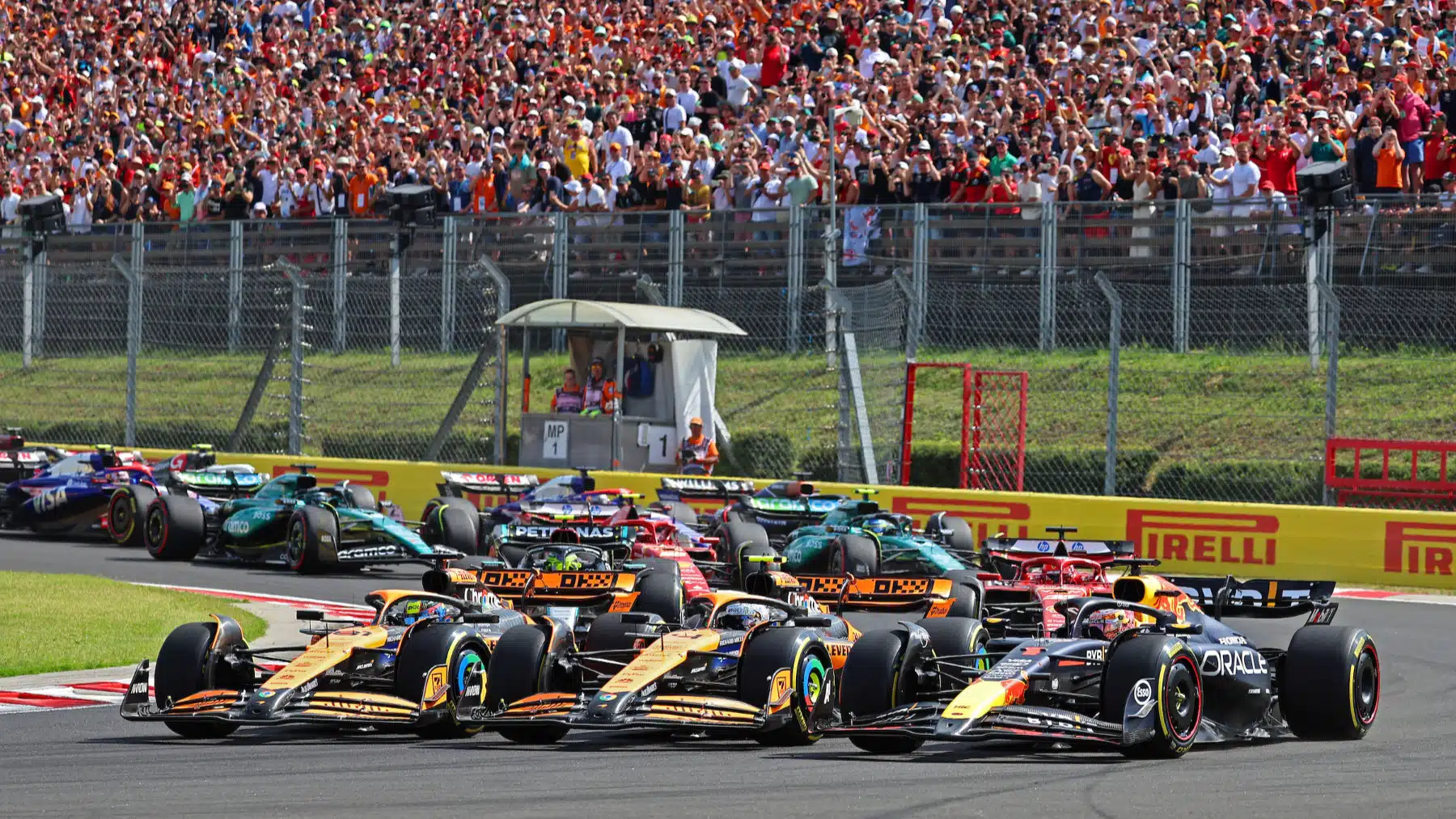 Oscar Piastri, Lando Norris (both McLaren-Mercedes) and Max Verstappen (Red Bull-Honda) side by side in the first corner after the start of the 2024 Hungarian Grand Prix
