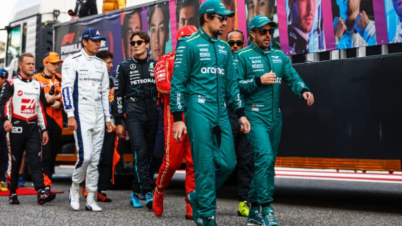 Fernando Alonso and Lance Stroll talk as they walk ahead of Formula 1 drivers
