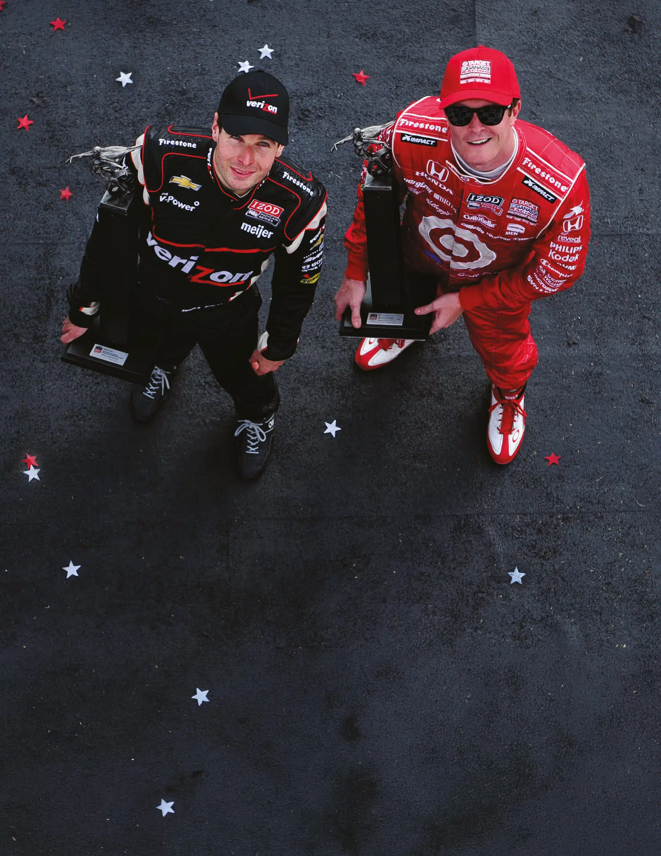 Will Power in Verizon Honda racing suit and Scott Dixon in Target Honda uniform holding trophies amid confetti after IndyCar victory celebration