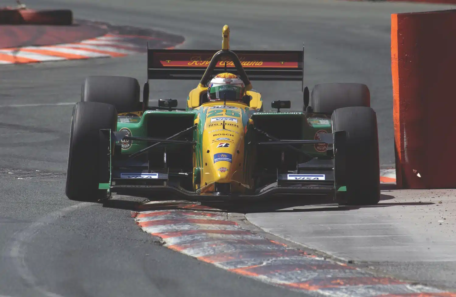Yellow green No.25 Formula 3 race car navigating corner with curbing at speed