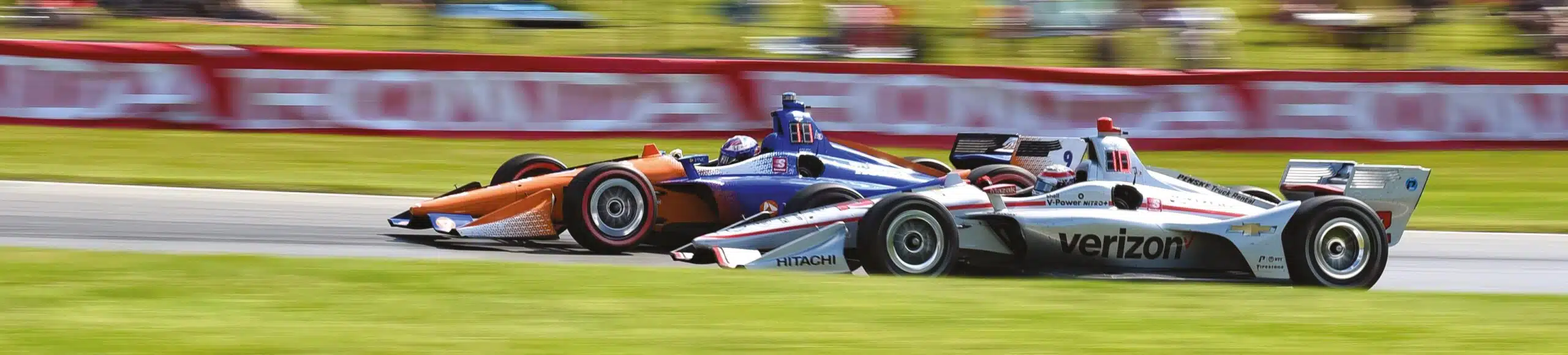 Will Power in white black red No.12 Verizon Hitachi Chevrolet IndyCar battles Scott Dixon in orange blue No.9 PNC Bank Honda on racetrack